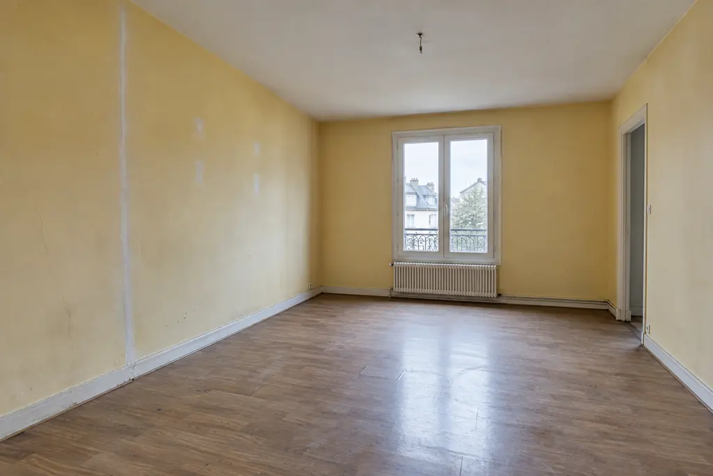 Simulation avant rénovation : séjour vide, murs jaunes à reprendre et sol usé.